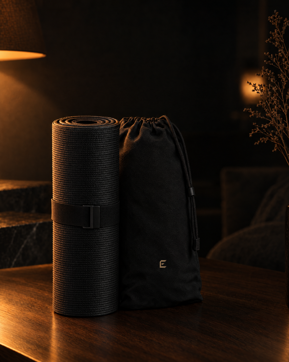Deep Delta Field Mat rolled beside its carry bag on a walnut surface at night